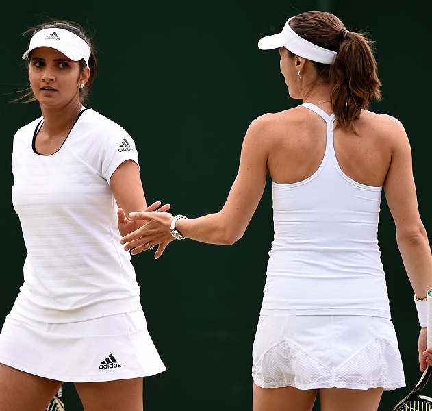 Switzerland's Martina Hingis (R) and India's Sania Mirza confer during their women's doubles third round match against Spain's Anabel Medina Garrigues and Spain's Arantxa Parra Santonja on day seven of the 2015 Wimbledon Championships at The All England Tennis Club in Wimbledon, southwest London, on July 6, 2015. RESTRICTED TO EDITORIAL USE -- AFP PHOTO / LEON NEAL